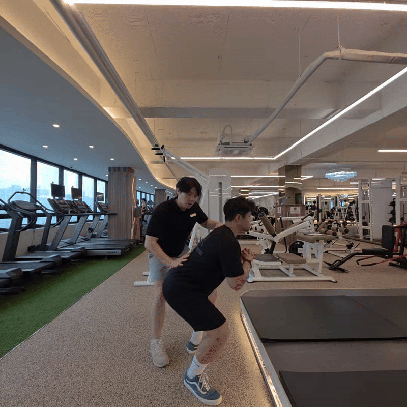 박대우 트레이너가 회원의 스쿼트 움직임을 지도하는 장면